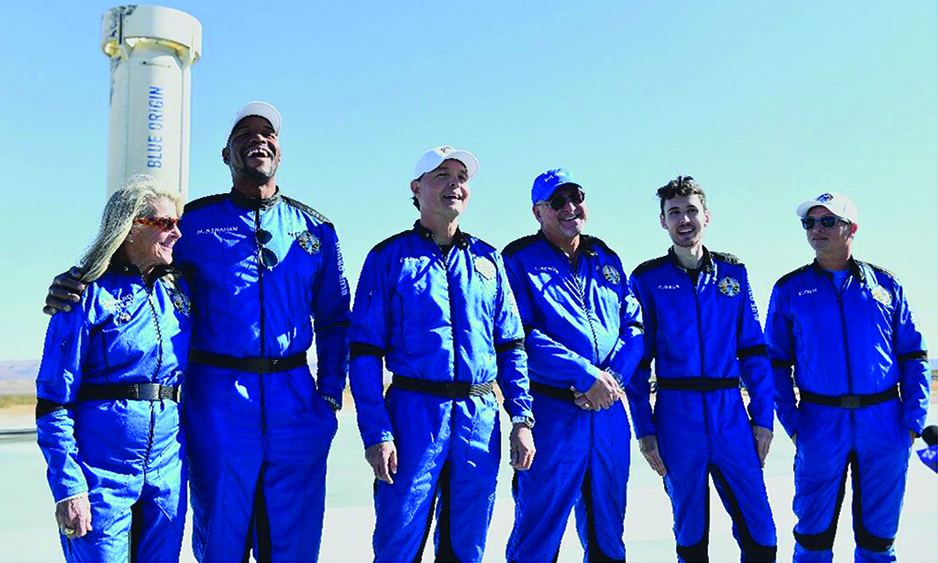 The Blue Origin NS-19 crew stand next to the New Shepard rocket after their successful launch on December 11, 2021.