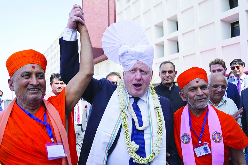 GANDHINAGAR, India: Britain's Prime Minister Boris Johnson (C) gets a traditional turban tied on his head upon his arrival at the Gujarat Biotechnology University in Gandhinagar on April 21, 2022.—AFP