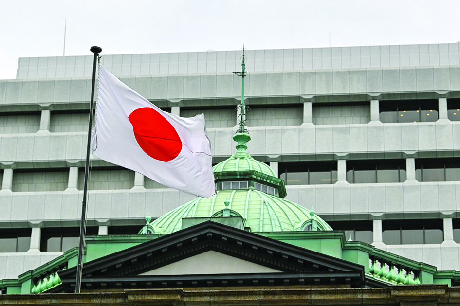 TOKYO: The Japanese flag flutters over the Bank of Japan (BoJ) head office building (bottom) in Tokyo.—AFP