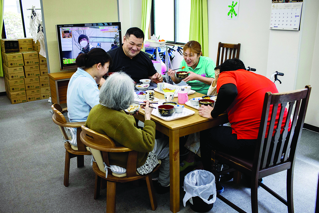 TOKYO: This picture taken on April 6, 2022 shows retired Japanese sumo wrestler and owner of the Hanasaki daycare center, Keisuke Kamikawa, who competed under the name Wakatenro, eating lunch with his family and elderly women at the center. - AFP