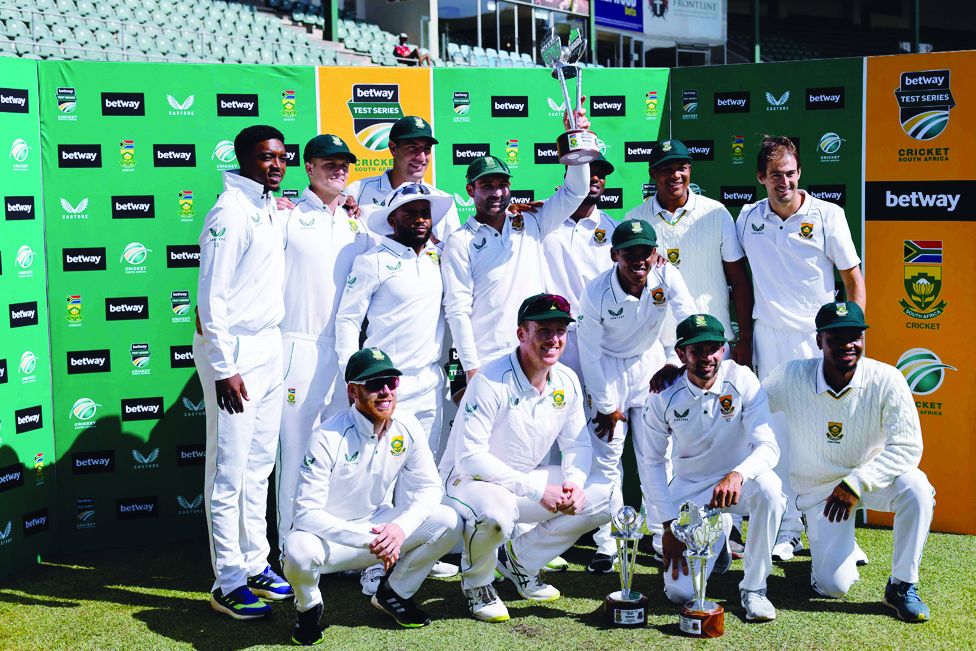 GQEBERHA, South Africa: South Africa's Dean Elgar holds the trophy as the South African team poses for a photo after winning the series following the second Test cricket match against Bangladesh at St George's Park on April 11, 2022. - AFP