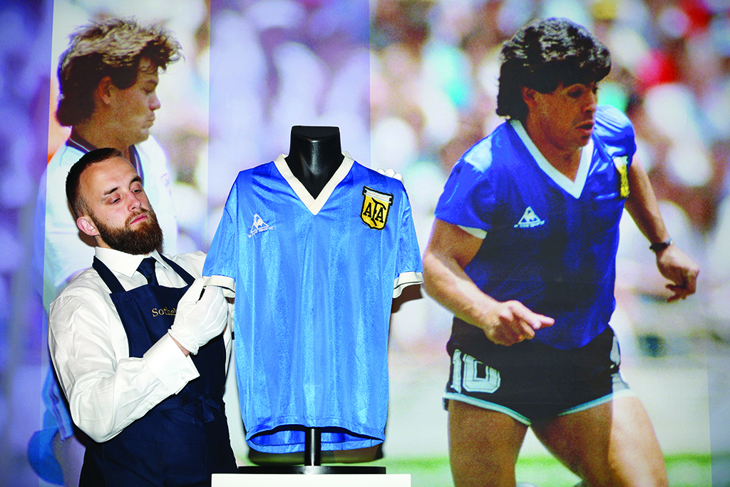 LONDON: A Sotheby's technician adjusts a football shirt worn by Argentina's Diego Maradona during the 1986 World Cup quarterfinal match against England during a photocall at Sotheby's auction house on April 20, 2022, ahead of its sale. - AFP