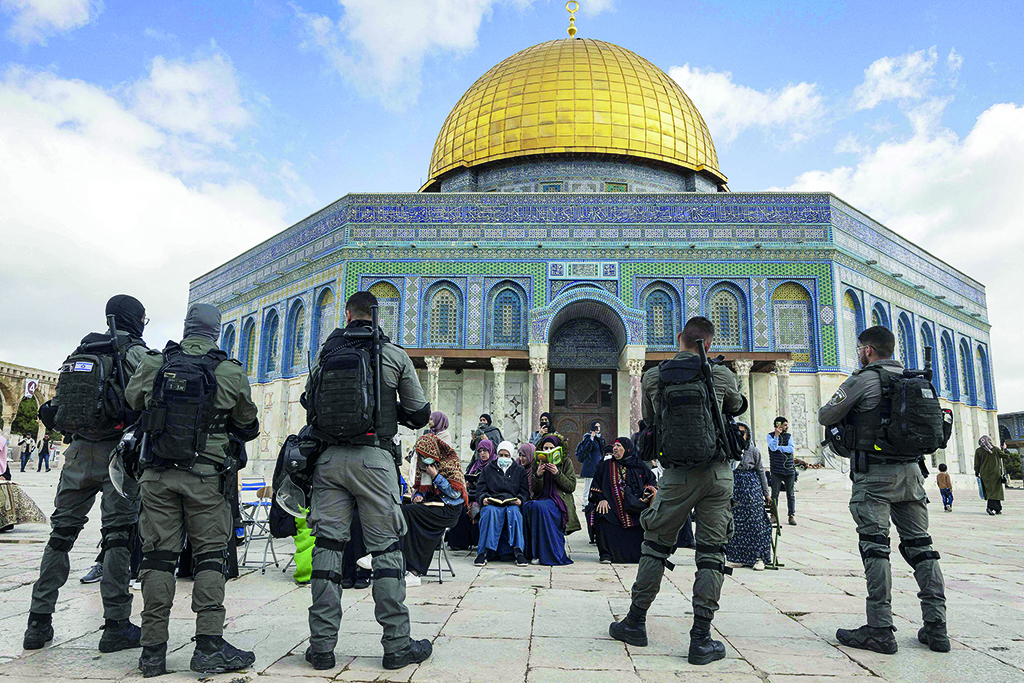 JERUSALEM: Zionist policemen stand guard in front of Muslim women praying in front of the Dome of the Rock mosque as a group of religious Jewish men and women visit the Temple Mount, which is known to Muslims as the Haram Al-Sharif (The Noble Sanctuary), at the Al-Aqasa mosques compound in the old city of Jerusalem on April 20, 2022. - AFP
