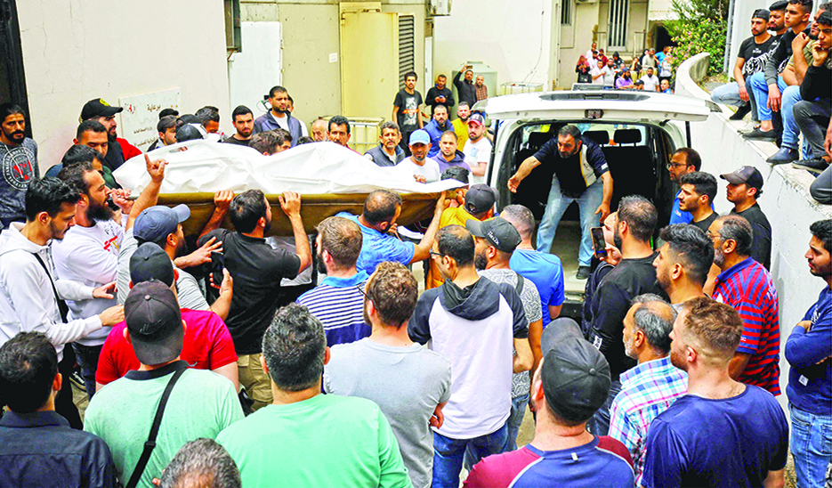 TRIPOLI: People gather at the entrance of the morgue of a hospital in Tripoli, as others carry the corpse of one of the people who died when their boat capsized a day earlier off the coast of the northern Lebanese city. – AFP