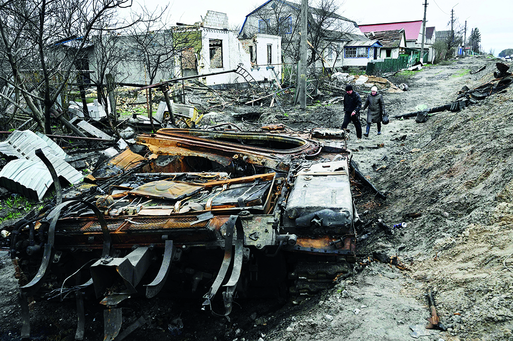 KYIV: Local residents walk amid debris of a charred Russian tank next to destroyed houses in the village of Zalissya, northeast of Kyiv during the Russian invasion of Ukraine. - AFP