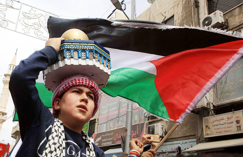 AMMAN: A young boy carries a replica of the Dome of the Rock mosque and waves a Palestinian flag as demonstrators march in the streets of the Jordanian capital Amman on April 22, 2022, to show solidarity with Palestinians.- AFP