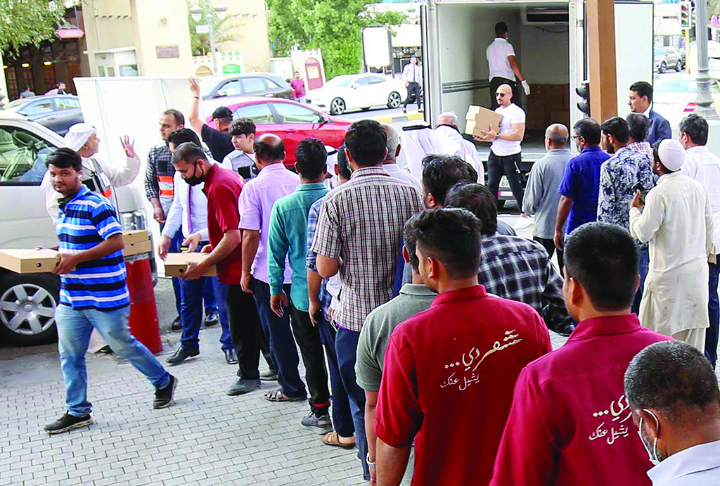 KUWAIT: Resident workers lining up to receive Iftar meals prior to the Maghreb prayer. - KUNA