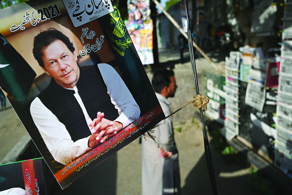 ISLAMABAD: A resident stands beside a picture of Pakistan's Prime Minister Imran Khan as he looks at the morning newspapers displayed for sale at a roadside stall in Islamabad on April 4, 2022, a day after Khan foiled an attempt to boot him from office. - AFP