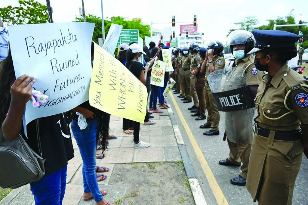 COLOMBO: Police stand guard as demonstrators take part in a protest against the surge in prices and shortage of fuel and other essential commodities near the parliament building in Colombo on April 7, 2022. - AFP