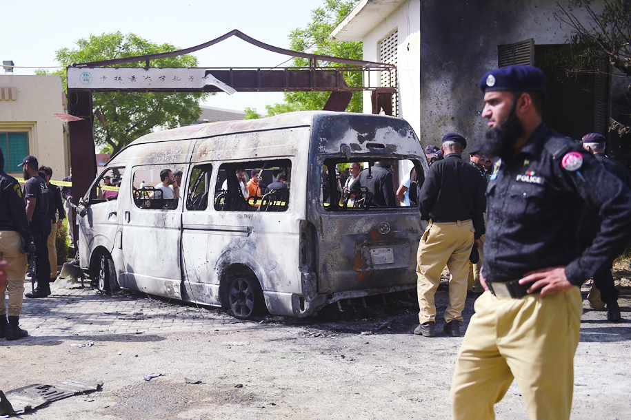 KARACHI: Police inspect a site around damaged vehicles following a suicide bombing near the Confucious Institute affiliated with the Karachi University, in Karachi. – AFP