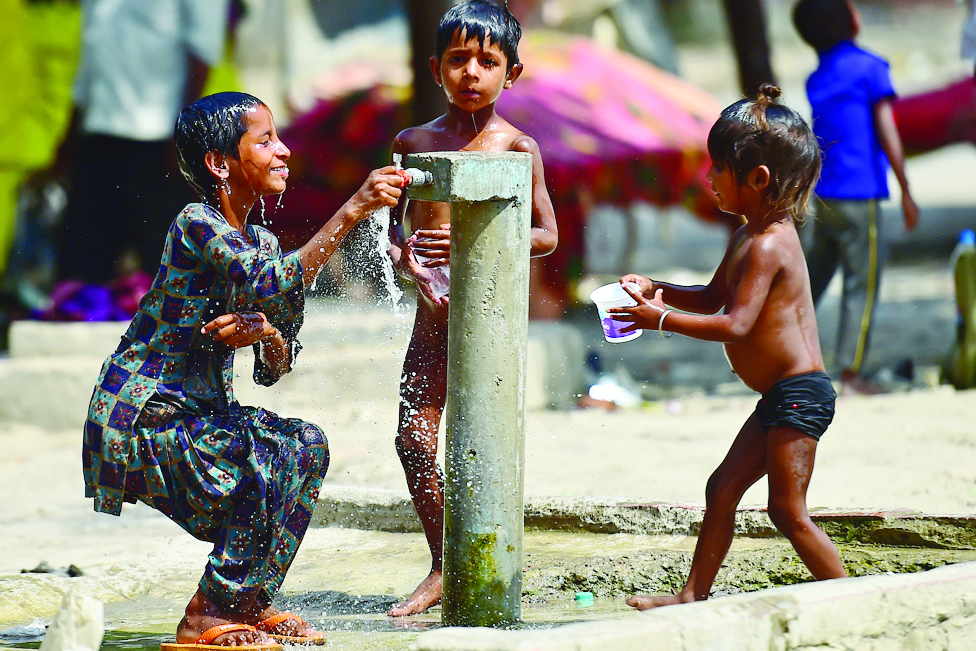 ALLAHABAD: Children take a bath from a roadside tap on a hot summer day in Allahabad on April 28, 2022. - AFP