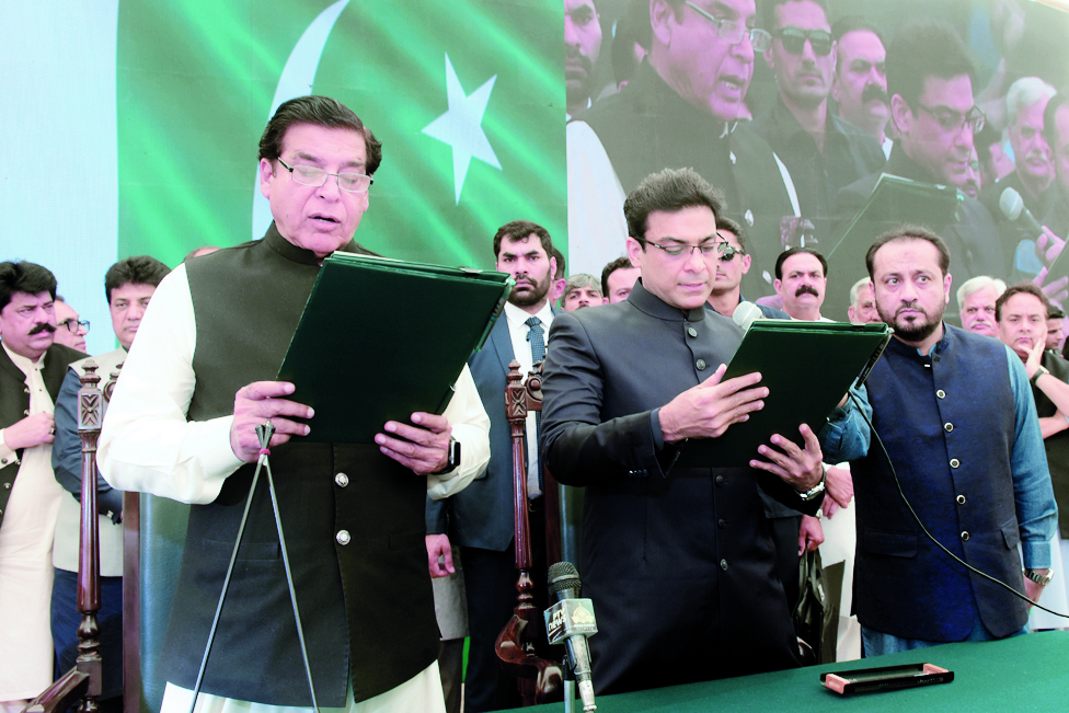 LAHORE: Photograph released by Punjab Press Information Department on April 30, 2022 shows the speaker of the national assembly, Raja Pervez Ashraf (L) administering the oath to Hamza Shehbaz Sharif (C), son of Pakistan's Prime Minister Shehbaz Sharif as the chief minister of Punjab province in Lahore. - AFP