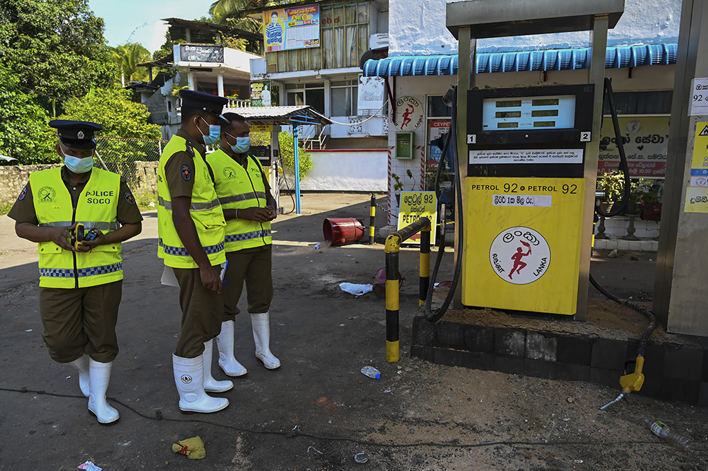 RAMBUKKANA, Sri Lanka: Police officers inspect a damaged Ceylon Petroleum Corporation fuel station in Rambukkana on April 20, 2022, a day after police killed an anti-government demonstrator while dispersing a protest against the high fuel prices and to demand President Gotabaya Rajapaksa's resignation over the worsening economic crisis. – AFP