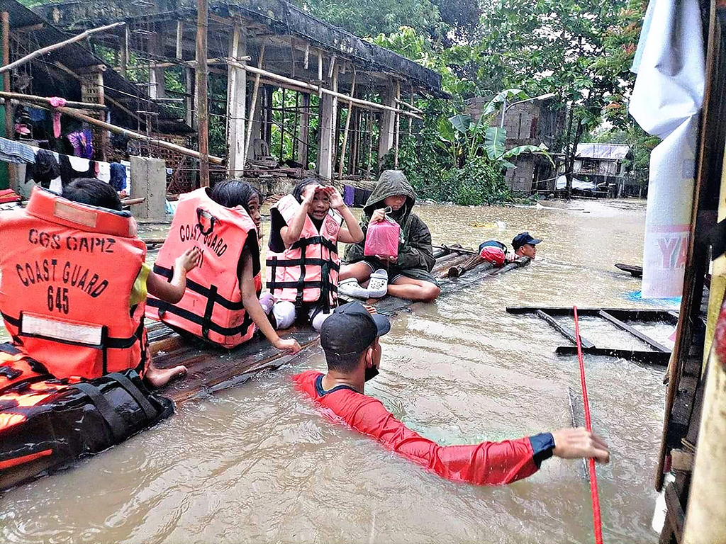PANITAN: Photo shows coast guard personnel evacuating local residents from their flooded homes on a makeshift raft in the town of Panitan, Capiz province as heavy rains brought on by Tropical Storm Megi inundated the area. - AFP