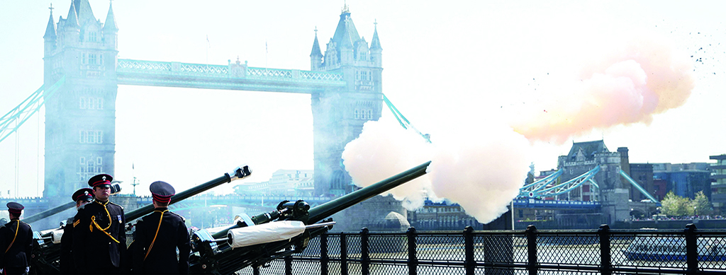 LONDON: Members of the Honorable Artillery Company stand guard during the fire of the 62 Gun Royal Salute for the Queen's Birthday, from Tower Wharf on April 21, 2022. (Inset) In this file photo, Britain's Queen Elizabeth II cuts a cake to celebrate the start of the Platinum Jubilee.- AFP