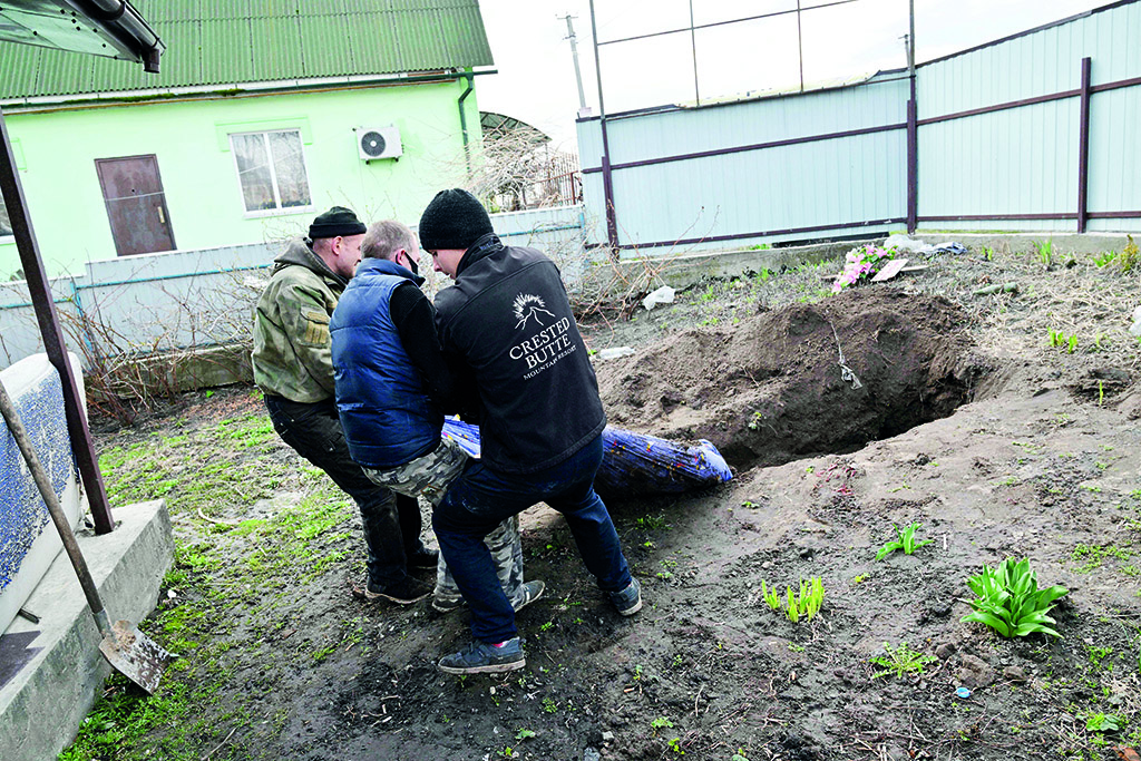 ANDRIIVKA: Workers exhume a body of a civilian man buried in the yard of his house in Andriivka village, Kyiv region, on April 11, 2022. - AFP