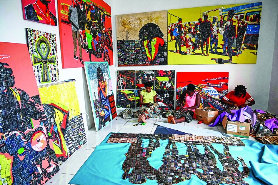 Workers of the Ivorian artist Mounou Desire Koffi (not seen) fix the reproduced image on a carpet, one of the stages in the making of artworks with used telephone keyboards in Bingerville, a commune of Abidjan.—AFP photos