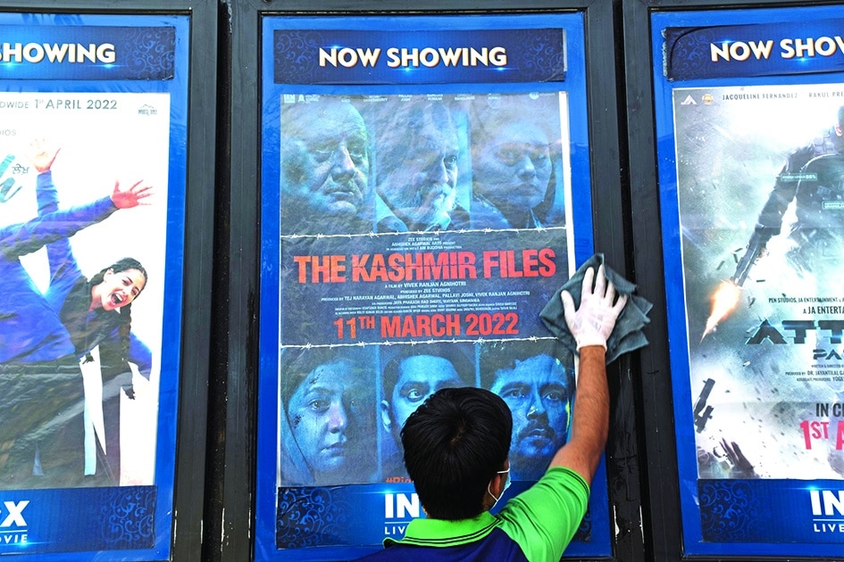  In this file photo a worker cleans a display with the poster of the Bollywood movie 'The Kashmir Files', outside a cinema hall in New Delhi.—AFP photos 