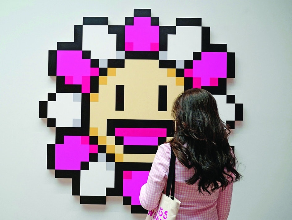 A person stands in front of artist Takashi Murakami’s “Murakami.Flower Pink & White”. 