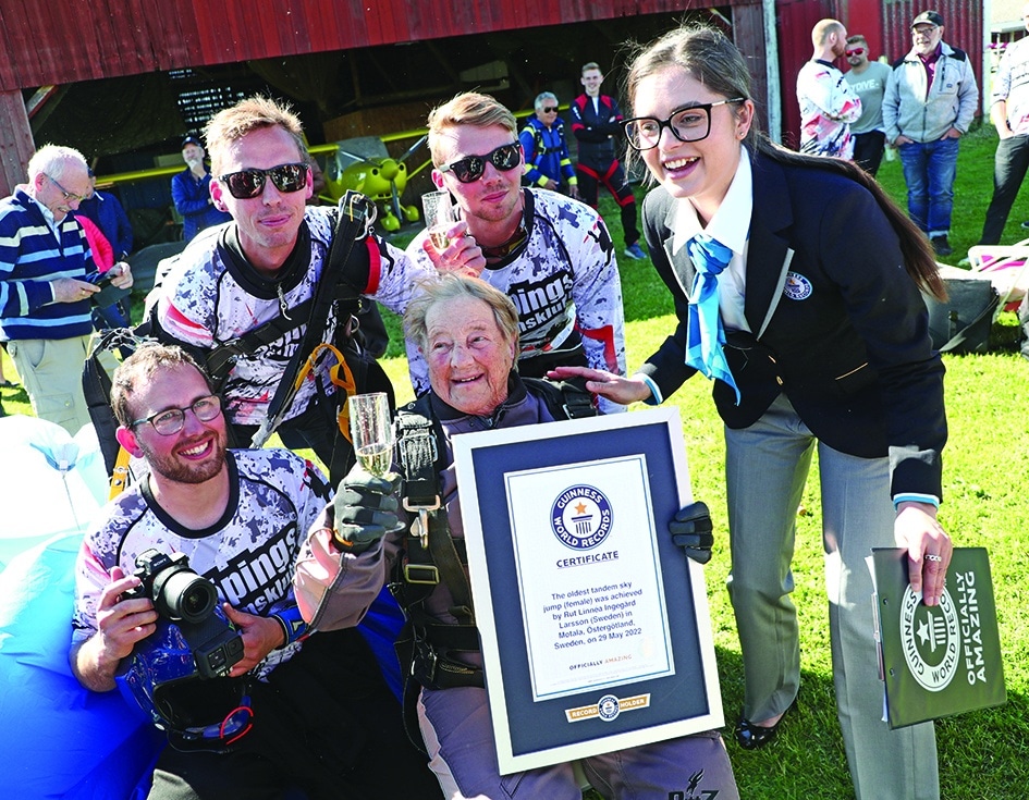 103-year-old Rut Larsson (center) from Mjolby is given her record certificate by Joanne Brent (right), controller at Guinness world records, and celebrates with parachutists from Linkoping's parachute club after she completed her jump in Motala, Sweden.—AFP photos