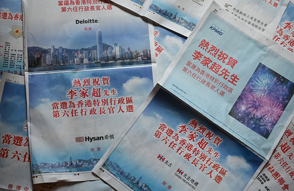 This photo illustration shows pages from two pro-Beijing newspapers in Hong Kong filled with advertisements from leading companies and business figures praising the selection of incoming chief executive John Lee on May 9, 2022. - Western multinationals and local tycoons published newspaper adverts on May 9  congratulating John Lee on becoming Hong Kong's next leader, following a rubber-stamp selection process the day before condemned by critics as anti-democratic. (Photo by Peter PARKS / AFP)