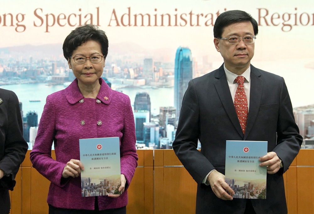 This file photo taken on July 1, 2020 shows Hong Kong's Chief Executive Carrie Lam (L) and Security Secretary John Lee (R) holding copies of the new national security law during a press conference at the government headquarters in Hong Kong. Hong Kong has emerged a more unequal city, its freedoms curtailed and international shine dulled after five years with Carrie Lam at the helm, analysts say, as her turbulent leadership draws to an end. — AFP