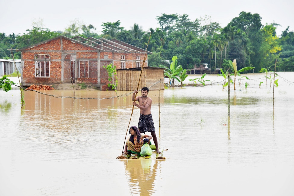 NAGAON, India: Villagers make their way on a raft past homes in a flooded area after heavy rains in Nagaon district, Assam state. Heavy rains have caused widespread flooding in parts of Bangladesh and India, leaving millions stranded and at least 57 dead.- AFP
