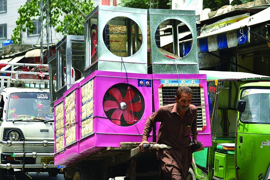 RAWALPINDI: A worker pulls a handcart loaded with air coolers at a market during a hot summer day in Rawalpindi.- AFP