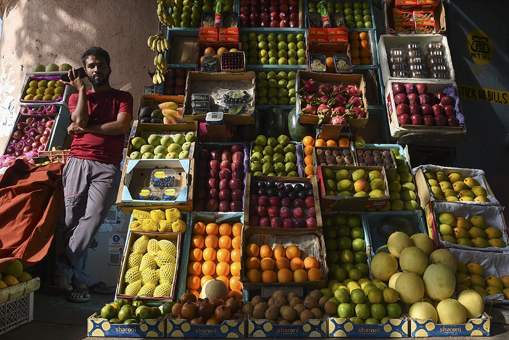 MUMBAI: A vendor speaks on a mobile phone as he waits for customers at a fruit stall in Mumbai on May 4, 2022. –AFP