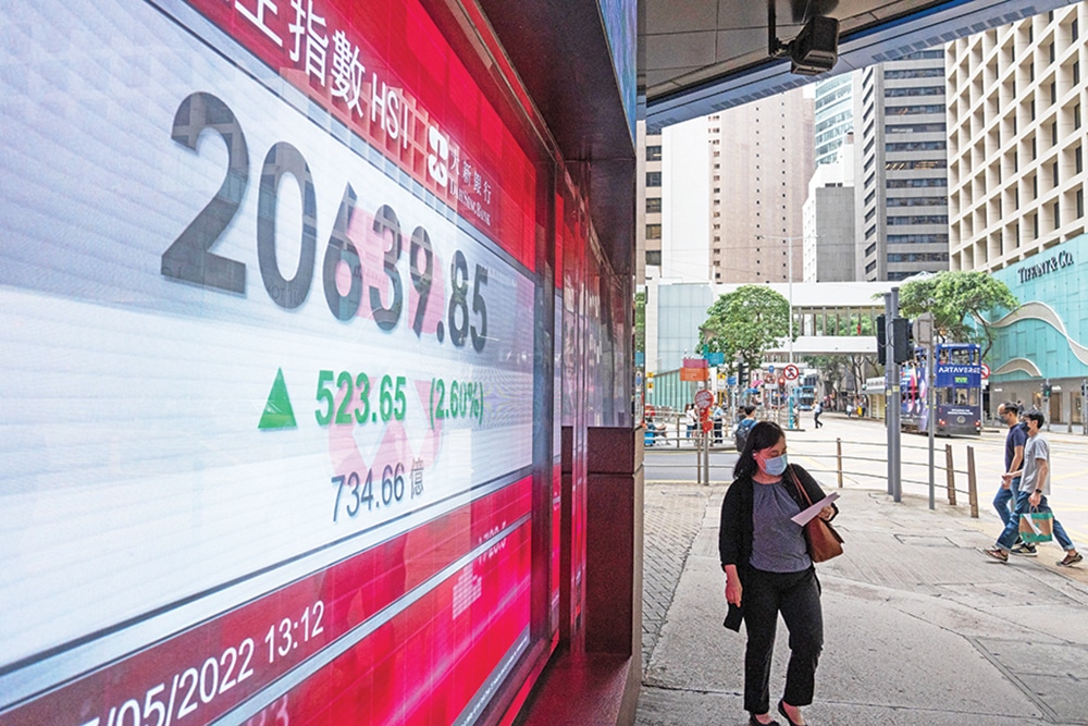 HONG KONG: A woman walks past an electronic display showing the Hang Seng Index in the Central district of Hong Kong on May 27, 2022. — AFP
