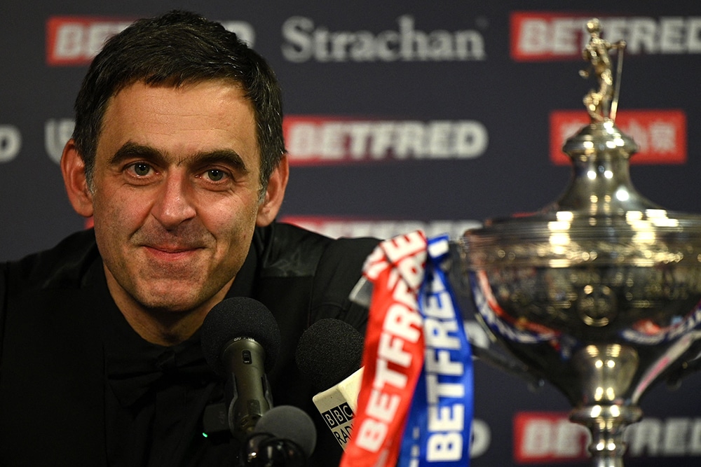 SHEFFIELD: England's Ronnie O'Sullivan speaks with members of the media, sitting with the trophy after his victory over England's Judd Trump in the World Championship Snooker final at The Crucible in Sheffield, England on May 2, 2022. - AFP