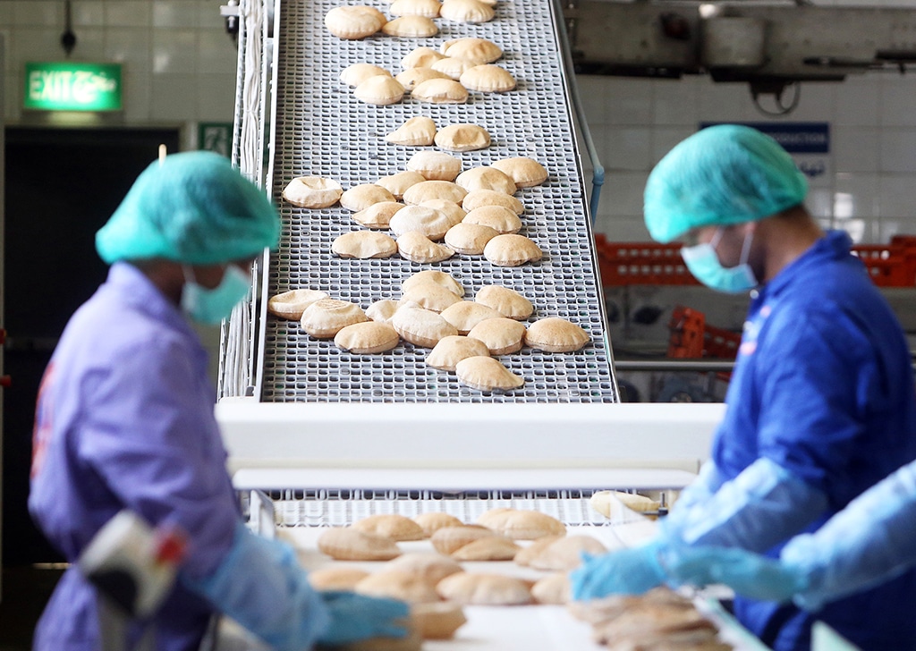 KUWAIT: Workers pack pita bread from a conveyer belt at a factory in this June 24, 2019 file photo. - Photo by Yasser Al-Zayyat