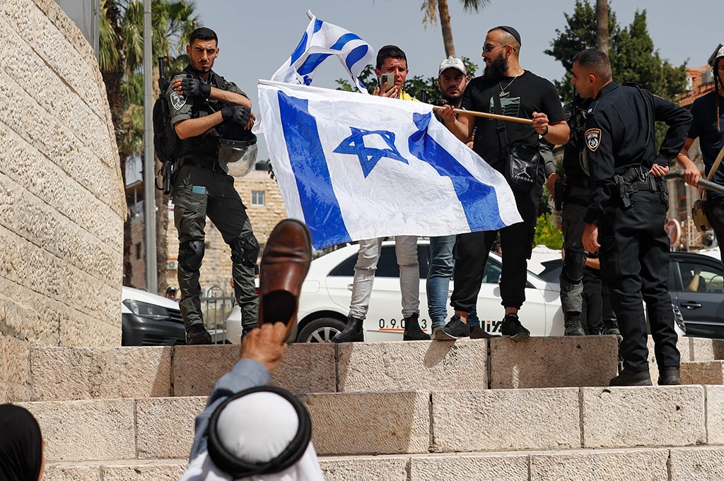 JERUSALEM: A Palestinian man raises a shoe against Zionists waving their national flags at Jerusalem Gate on May 29, 2022. - AFP