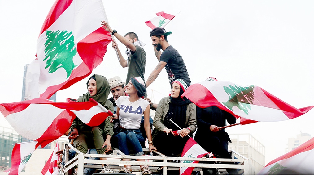 BEIRUT: In this file photo taken on Oct 20, 2019, young Lebanese demonstrators wave national flags as they take part in a rally in the capital's downtown district. - AFP