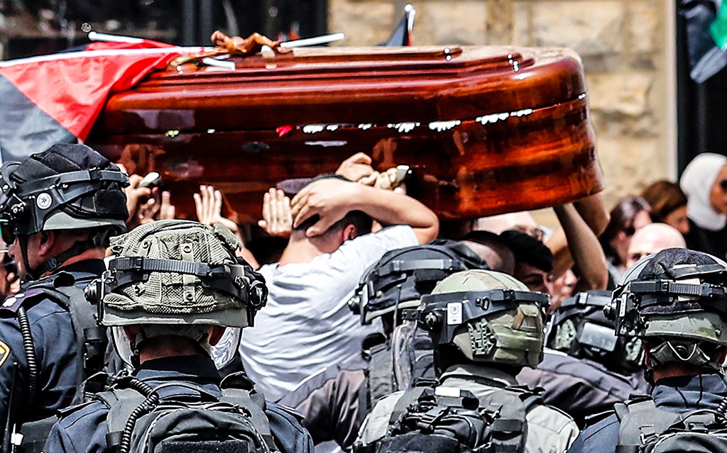 JERUSALEM: In this file photo taken on May 13, 2022, Amro Abu Khudeir (gray shirt) covers his head protectively as he carries the casket of slain Al-Jazeera journalist Shireen Abu Akleh out of a hospital, before being transported to a church and then her resting place, in Jerusalem. -- AFP