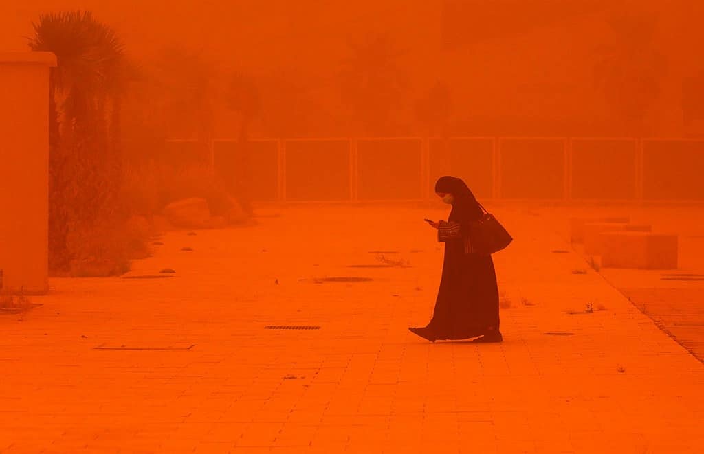 KUWAIT: A woman browses a phone as she walks amidst a severe dust storm in Kuwait City on May 23, 2022. -- Photo by Yasser Al-Zayyat