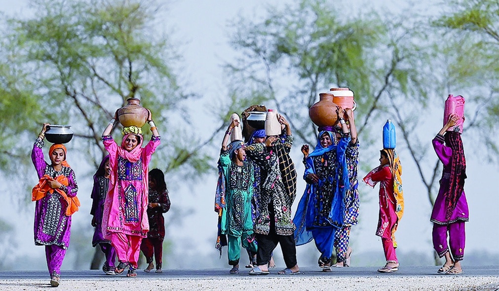 JACOBABAD, Pakistan: Women walk towards their homes carrying drinking water in containers during heatwave in the outskirts of Jacobabad, in southern Sindh province. - AFP