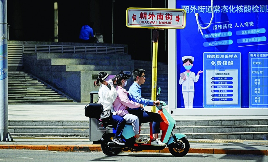 BEIJING: People commute on an electric bicycle in Beijing on May 26, 2022. - AFP