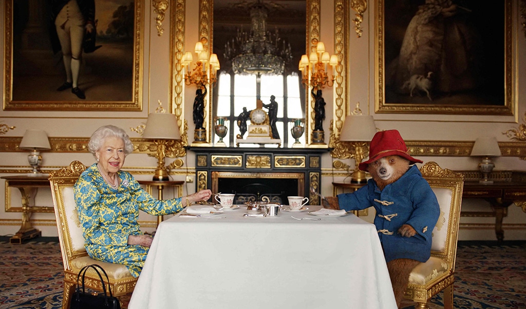 An undated handout photograph released by Buckingham Palace shows Queen Elizabeth II and Paddington Bear having cream tea at Buckingham Palace, taken from a film that was shown at the BBC Platinum Party at the Palace.—AFP photos