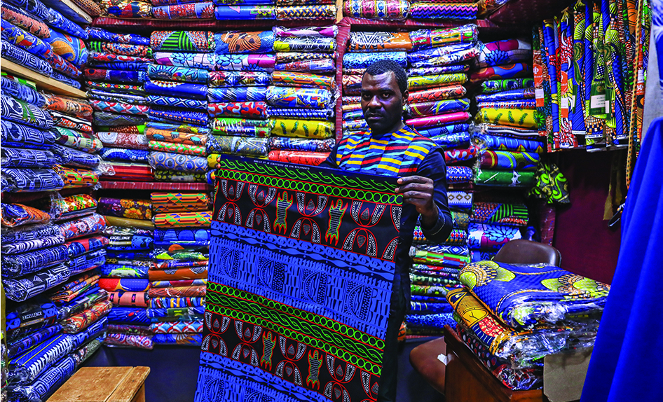 A trader holds a piece of ndop cloth in his shop at Market B in Bafoussam. — AFP photos