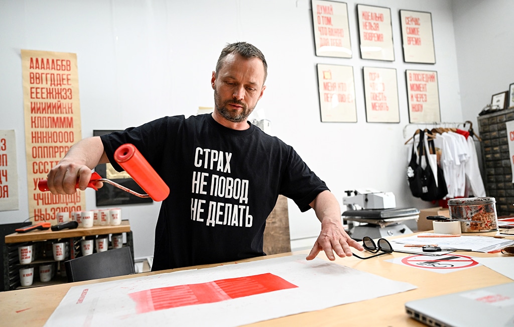 Sergei Besov, the 45-year-old artist and the Partisan Press poster workshop founder, wearing a black T-shirt with a slogan reading “Fear is no reason not to act” makes a poster using an old manually-operated printing press in his workshop in Moscow.—AFP photos 