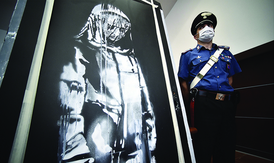 In this file photo A policeman stands guard near a piece of art attributed to Banksy, that was stolen at the Bataclan in Paris in 2019, and found in Italy, ahead of a press conference in L’Aquila. — AFP