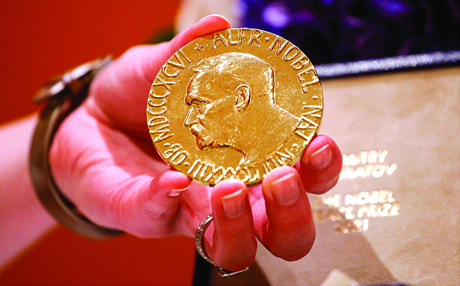 A woman holds Russian journalist Dmitry Muratov's 2021 Nobel Peace Prize medal in New York. —AFP photos