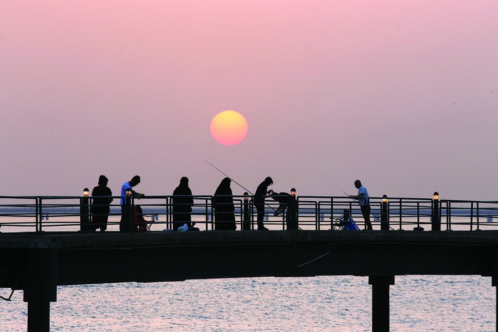 KUWAIT: People fish from a pier at sunset in Kuwait City, on June 13, 2022. -- Photo by Yasser Al-Zayyat
