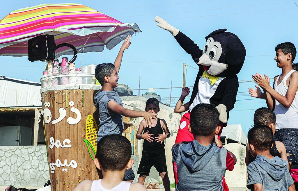 GAZA: Palestinian corn vendor Muhammad Mukhaimer entertains young customers at the beach in Rafah on June 13, 2022. - AFP