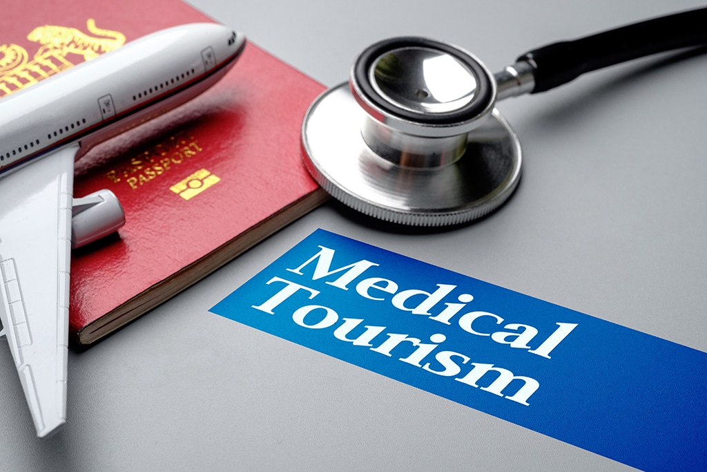 Medical Tourism, medical travel concept. Stethoscope, toy plane and passport on grey background. Selective focus image.