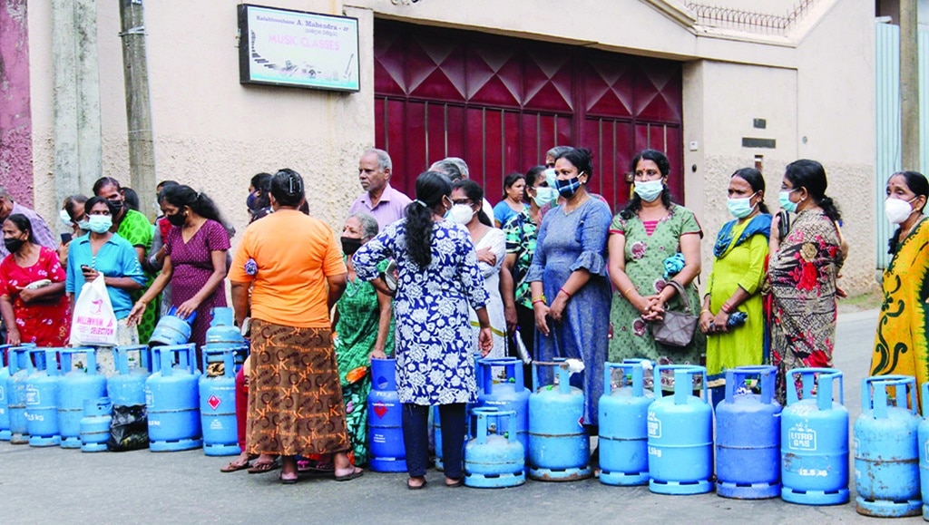 COLOMBO: People stand beside empty Liquefied Petroleum Gas (LPG) cylinders as they block a road to protest against paucity of fuel and cooking gas in Colombo on June 7, 2022. -AFP