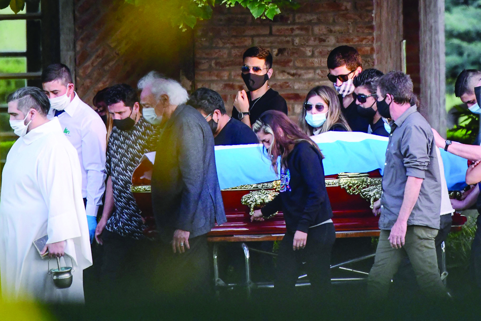 BELLA VISTA: In this file photo, the coffin with the remains of late Argentine football legend Diego Armando Maradona is carried by his family and friends at the Jardin Bella Vista cemetery, in Buenos Aires province. Eight medical personnel will stand trial for alleged criminal negligence in the death of Argentine football legend Diego Maradona, according to a court ruling made public on June 22, 2022. - AFP