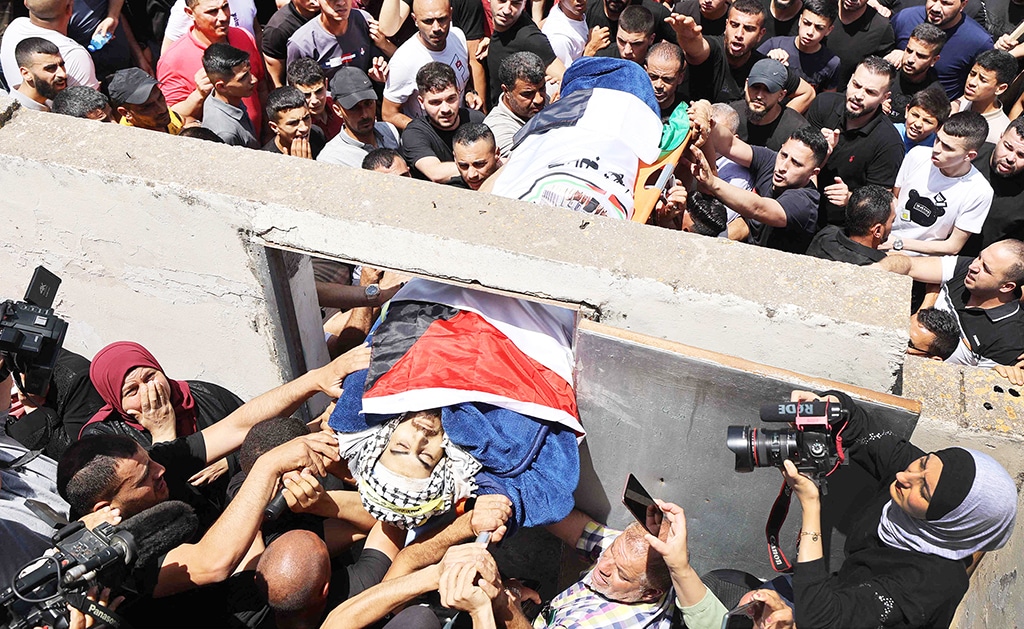 JENIN: Mourners carry the flag-draped body of a Palestinian youth killed by Zionist troops in the town of Yabad a day earlier during his funeral on June 2, 2022. - AFP