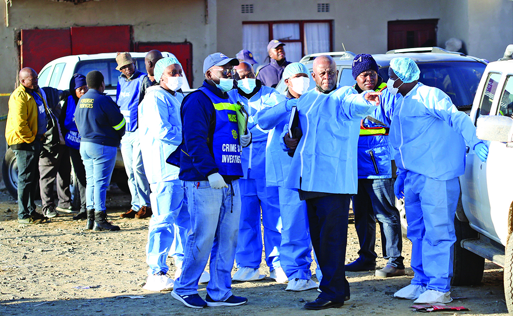 EAST LONDON, South Africa: Police and investigators put on protective clothing before going into a township pub in South Africa's southern city of East London, after 20 teenagers died.  - AFP